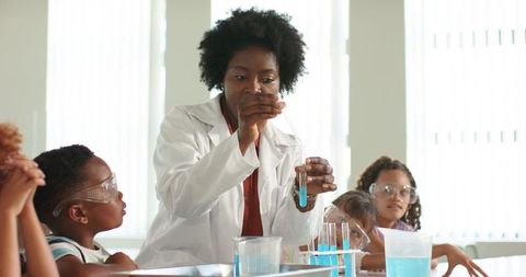 African american teacher demonstrating chemistry experiment with elementary students hands-on lab