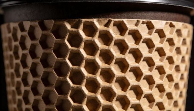 Macro honeycomb cardboard sleeve wrapping cylindrical container with black rim and texture