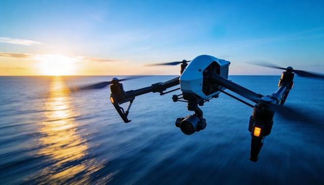 Hovering Professional Quadcopter Drone with Gimbal Camera over Sunset Ocean Horizon
