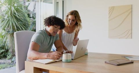 Young couple collaborating on laptop at home workspace