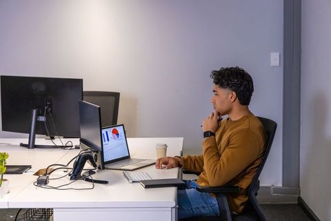 Asian professional reviewing laptop dashboards and analytics on modern minimalist office desk