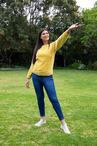 Asian Woman Enjoying Leisure in Lush Backyard with Vibrant Yellow Sweater