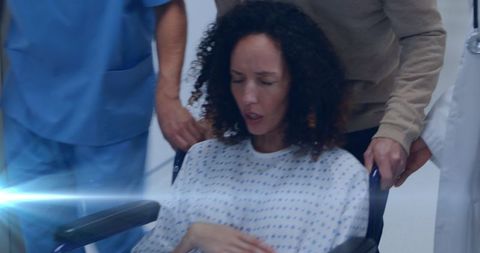 Pregnant Woman in Wheelchair with Nurse and Supportive Partner in Hospital