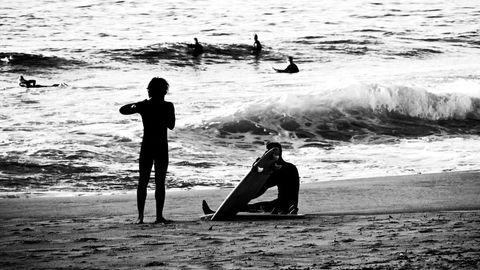 Surfers at Sunset with Waves on Sandy Beach