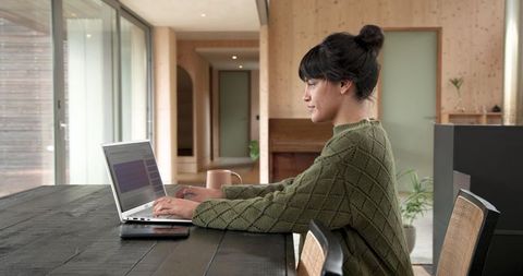 Asian Woman Working on Laptop in Cozy Minimalist Setting