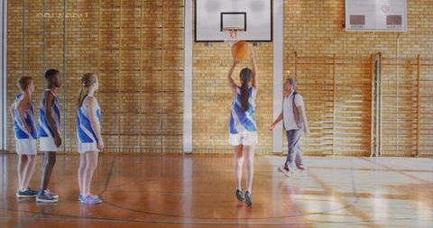 Teen Basketball Players Practicing Free Throws in School Gym