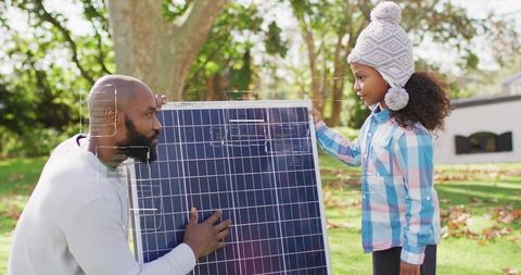 Parent and Child Holding Solar Panel in Backyard Teaching Renewable Energy DIY