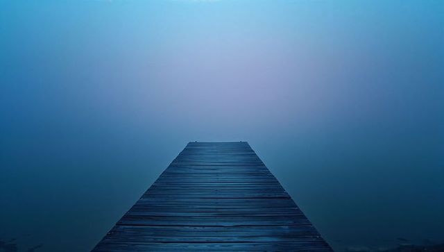 Foggy wooden dock by tranquil lakeside evoking serenity