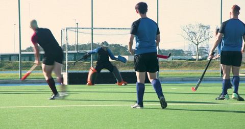 Field hockey players practicing with intense focus on goal area