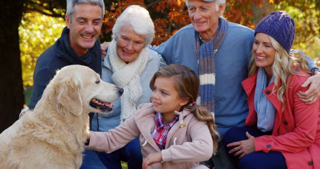 This image portrays a multigenerational family enjoying quality time with their golden retriever in an autumn park. The vibrant fall colors and relaxed expressions highlight family bonding and seasonal leisure activities. Use this image for marketing campaigns focused on family values, pet care, aging, and seasonal outdoor activities.