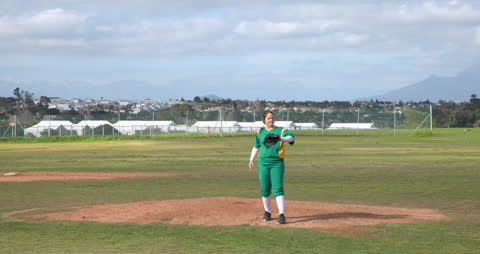Female Baseball Player in Action on Pitcher's Mound Preparing Pitch