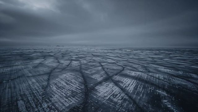 Stretching arctic ice field revealing polygonal cracks and snow streaks