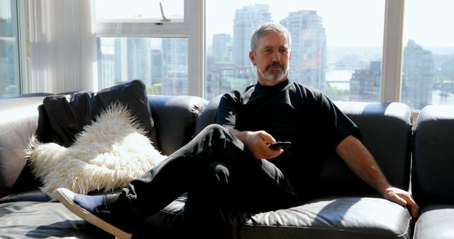 Relaxing Middle-aged Man Watching TV in Modern Apartment with City View - Download Free Stock Images Pikwizard.com