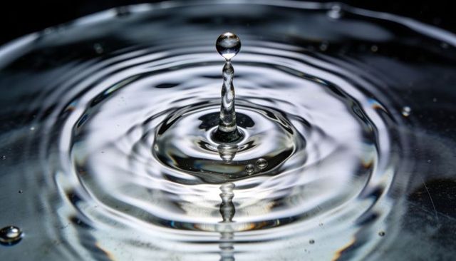 Macro spherical water droplet forming crown with concentric ripples and mirror reflection