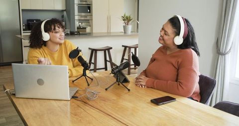Recording cozy home podcast with diverse female cohosts chatting, laughing, collaborating
