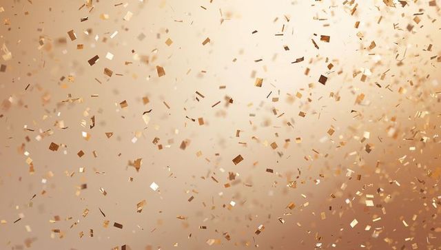 Scattering metallic gold and copper confetti creating warm shimmering bokeh backdrop