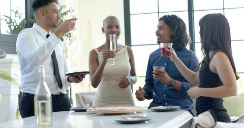 Friends raising glasses around kitchen island during elegant cocktail gathering