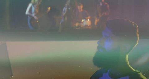 Bearded man watching rock band performance on monitor