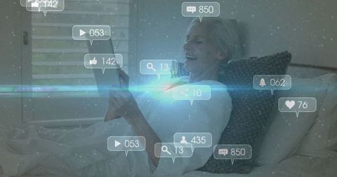 Smiling Senior Woman Engaging with Digital Device on Bed