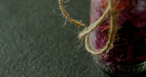 Rustic glass jar with purple botanicals and twine on dark countertop
