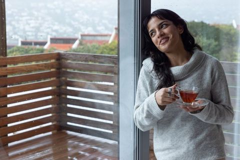 Woman Enjoying Tea by Daylight, Embracing Peaceful Home Atmosphere