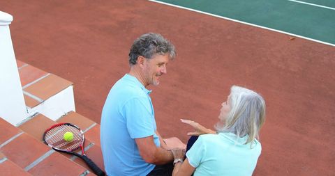 Elderly Couple Enjoying Conversation by Tennis Court