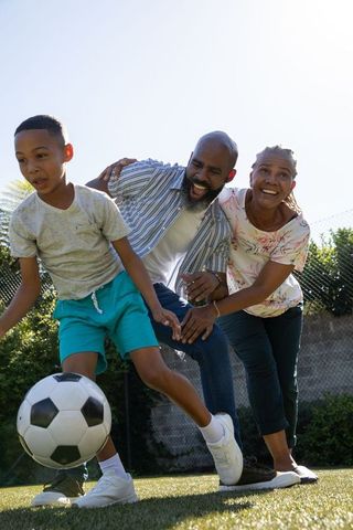 Family enjoying soccer game in sunlit backyard