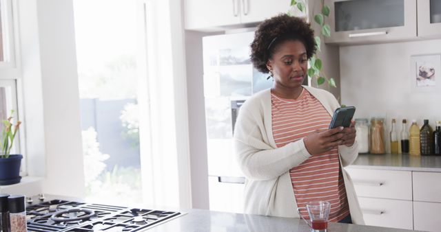 African American Woman Messaging in Modern Kitchen with Sunlight - Download Free Stock Images Pikwizard.com