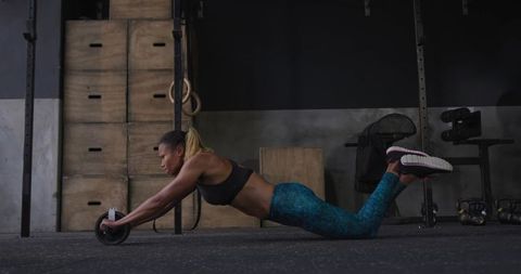 Athletic Woman Performing Ab Wheel Rollout on Gym Floor