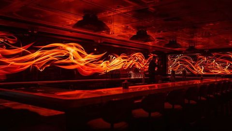 Neon Flame Light Trails Flowing Through Dark Lounge Bar Reflecting on Polished Counter