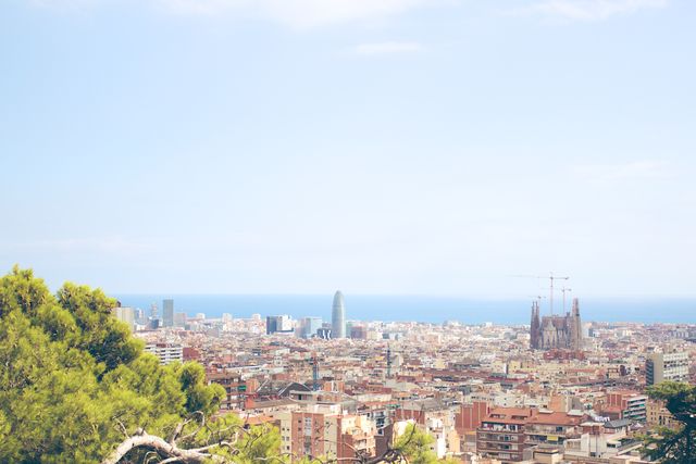 Image shows a wide view of Barcelona's urban landscape with the sea in the background. Significant landmarks like Sagrada Familia and modern buildings are visible. Suitable for tourism promotions, travel blogs, website banners, postcards, and city guides.