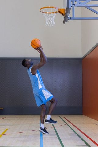 African American Athlete Jumping for Basketball Slam Dunk in Gym