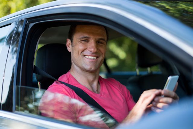 Portrait of smiling man using mobile phone while traveling in car