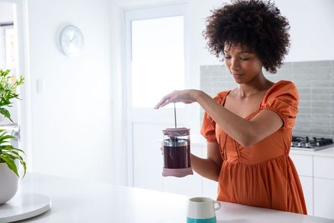 Woman Brewing Coffee with French Press in Contemporary Kitchen