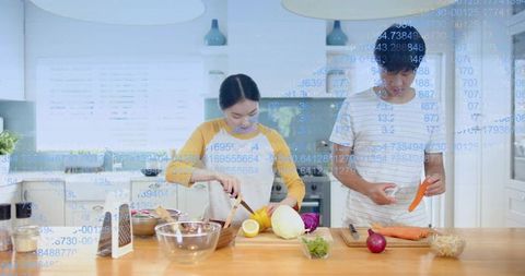 Young couple preparing vegetables in bright modern kitchen with blue data overlay