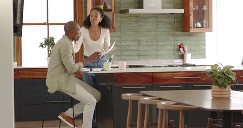Diverse couple sharing morning discussion over documents in kitchen