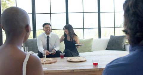Couple enjoying relaxed gathering on sofa with friends in bright modern living room