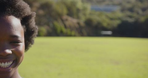 Smiling child in sunlit field reflecting carefree joy