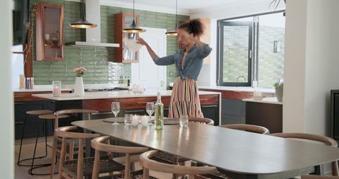 Joyful woman preparing festive table in modern kitchen
