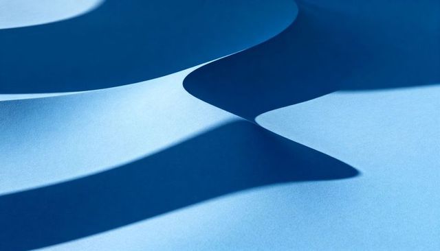 Abstract blue paper waves creating smooth curves and sharp shadows for minimal design