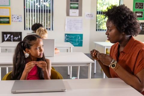 African american teacher guiding girl with hands-on geometry model in bright classroom
