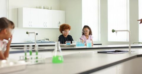 African American children conducting colorful chemistry experiment in bright laboratory