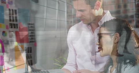 Professionals collaborating over laptop, brainstorming with notes in modern workspace