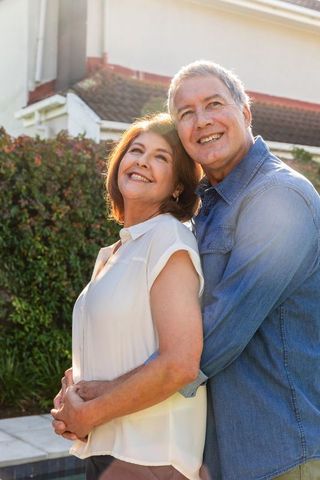 Senior Couple Embracing Outdoors by Poolside and Garden