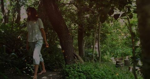 Woman Walking Barefoot on Path in Tranquil Garden with Sunlit Foliage