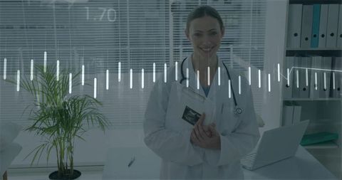 Smiling female obstetrician holding ultrasound scan wearing stethoscope in clinic office