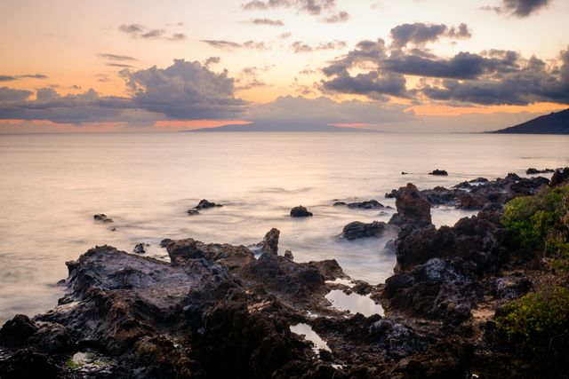 Beautiful coastal scene capturing a tranquil sunset over rocky formations by the sea. Perfect for use in travel promotions, nature blogs, relaxation content, and scenic wallpapers. Highlights the serene atmosphere and beauty of coastal landscapes during evening hours.