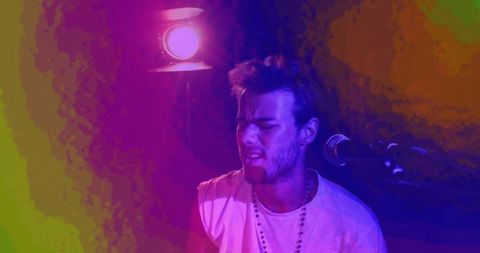 Male musician singing in vibrant studio dramatic lighting