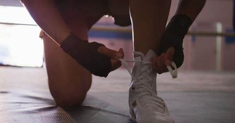 Boxer preparing tying laces in boxing ring ready for match