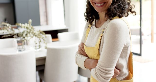 Smiling Woman in Yellow Apron Standing with Arms Crossed - Download Free Stock Images Pikwizard.com